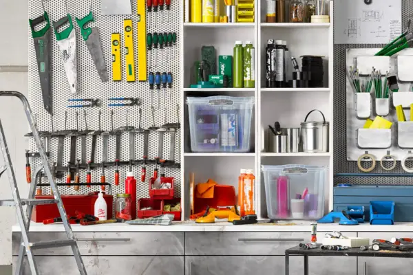 Werkzeugwand mit Sägen, Wasserwaagen, Schraubendrehern und Zangen. Regale mit Behältern und Flaschen. Ein perfektes Ideen Garage Ordnungssystem.