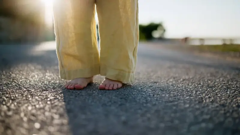 Barfuß auf Asphalt, die weite Leinenhose im Abendlicht. Ein Gefühl von Freiheit, als ob die Hose frisch gewaschen wäre und bereit für neue Abenteuer.